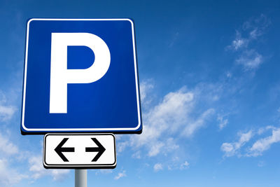 Low angle view of road sign against blue sky