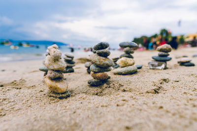 Close-up of pebbles on sand at beach against sky