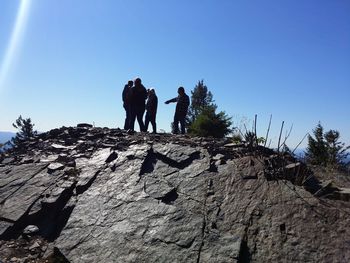 Low angle view of silhouette people standing on rock