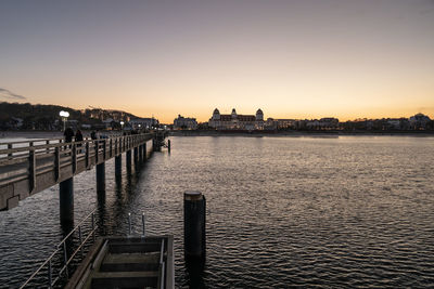 Pier over sea against clear sky during sunset