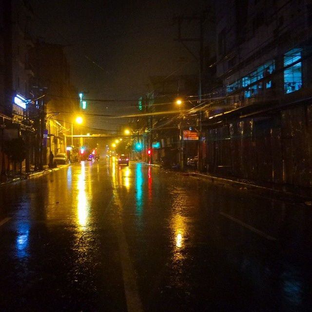 illuminated, night, building exterior, city, street light, street, built structure, architecture, wet, transportation, reflection, rain, water, car, lighting equipment, city street, city life, road, mode of transport, season