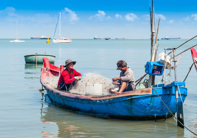 Fishermen in boat against sky
