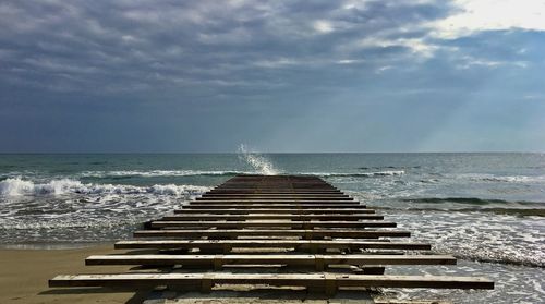 Liguria, waves hitting a pier in a cloudy day