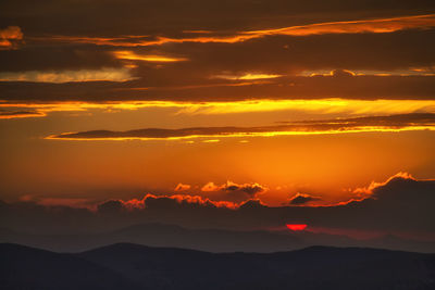 Scenic view of silhouette mountains against orange sky
