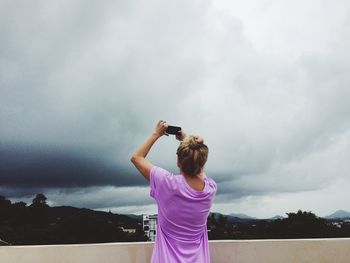 Rear view of woman photographing sky through mobile phone