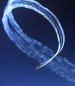 Low angle view of airshow against clear blue sky