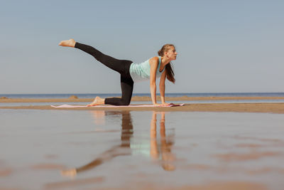 Side view of woman exercising at beach