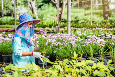 Rear view of woman working on flowering plants