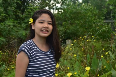Portrait of smiling young woman standing against trees