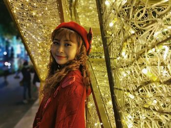 Portrait of cute girl standing against illuminated christmas lights