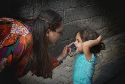 Woman with girl standing on footpath