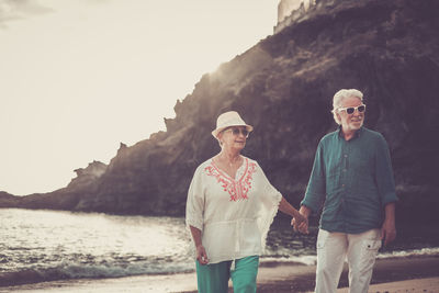 Senior couple holding hands on shore at beach