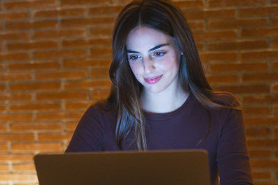 Young woman using laptop while sitting on table