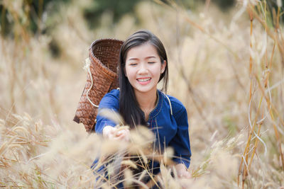 Young woman wearing traditional clothing while carrying basket amidst crops at farm