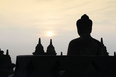 Silhouette statue of temple against sky during sunset