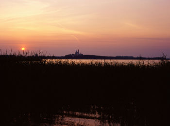 Calm lake along landscape at sunset