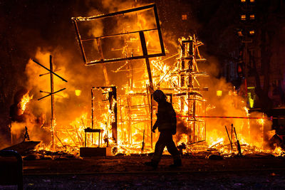 Side view of firefighter walking on land against burnt built structures