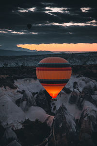 Hot air balloon on rock against sky during sunset