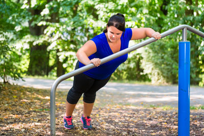 Full length of woman holding umbrella against trees