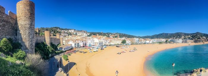 Panoramic view of beach and buildings against blue sky