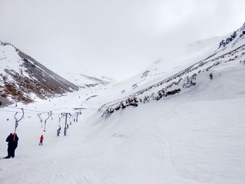 People skiing on snowcapped mountain against sky