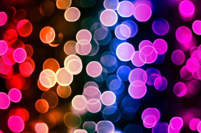 Defocused image of multi colored illuminated lights against black background