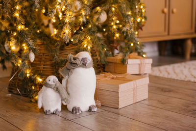 Toy penguins and gifts under the christmas tree with lights