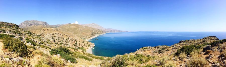 Panoramic view of sea and mountains against clear blue sky