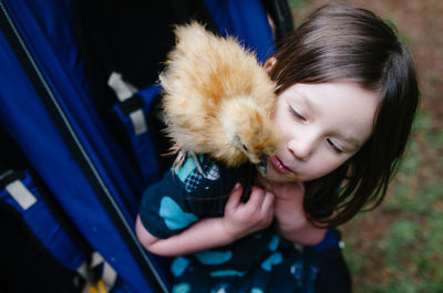 High angle view of baby chicken on girl's shoulder at park in baby carriage