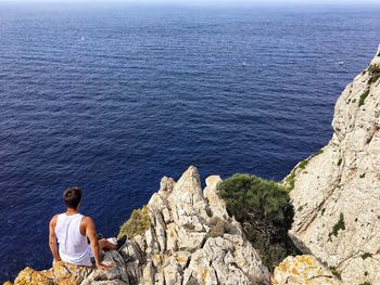 Man sitting on rock by sea