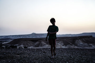 Full length of child standing on land against sky during sunset