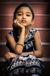 Portrait of cute girl with hand on chin sitting at steps