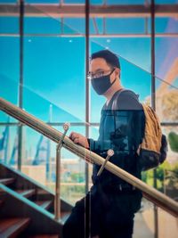 Side view of man on staircase against floor to ceiling glass panels.