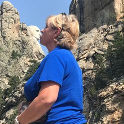 Low angle view of woman standing on cliff against clear blue sky