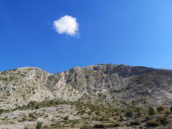 Low angle view of rocky mountain against blue sky