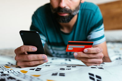 Close up hand holding credit card and shopping online on bed.