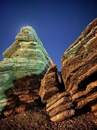 Low angle view of rock formations against clear blue sky