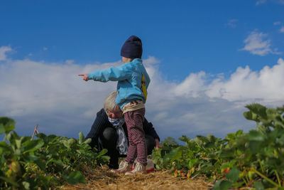 Rear view of boy on field against sky