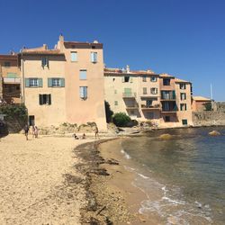 Buildings by sea against clear sky