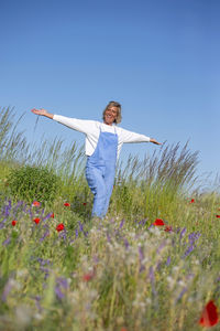 Young woman standing on field against clear sky