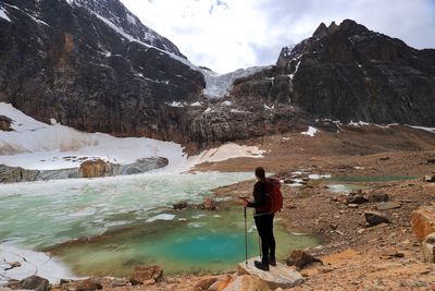 Rear view of woman standing on rocks at a glacier