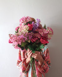 Woman wearing pink boho dress standing indoors holding bouquet of flowers