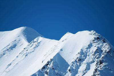 Scenic view of snowcapped mountains against clear blue sky