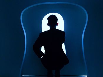 Rear view of silhouette man looking through window