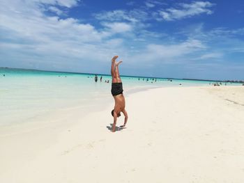 Full length of shirtless man on beach against sky