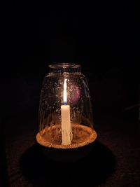 Close-up of illuminated tea light candles on table in darkroom