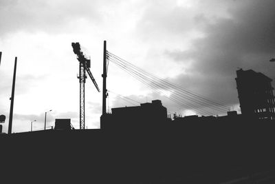 Low angle view of crane against cloudy sky