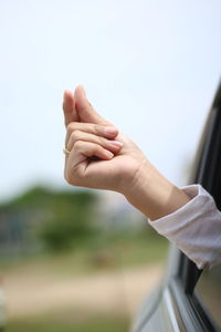 Cropped hand of woman snapping by car window