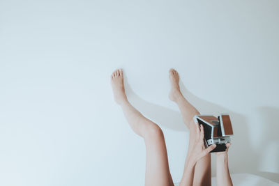 Low section of woman holding hands over white background