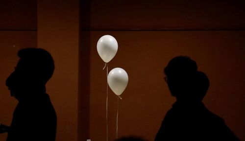 Silhouette of two people standing against wall